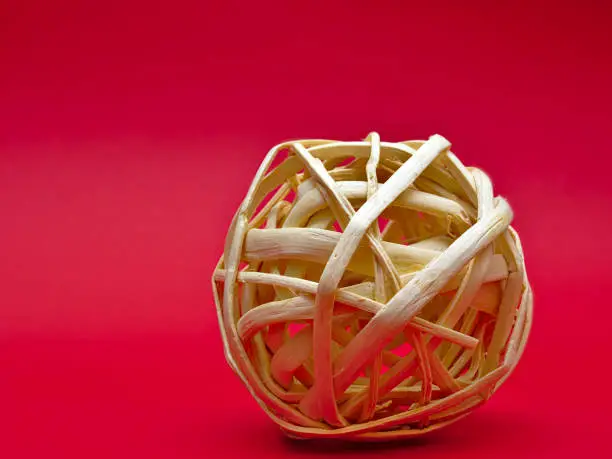Photo of Decorative rattan ball isolated on red background with copy space.
