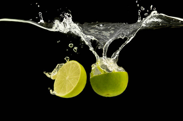 istock Ripe lime halves splashing in clear water 1162288053