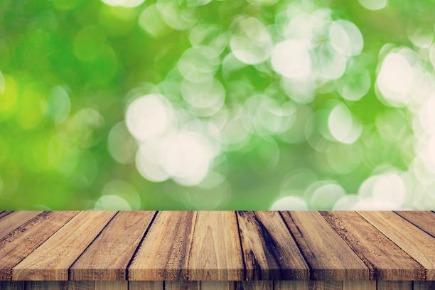 istock Empty wooden table and abstract blurred green bokeh leaves background texture, display montage with copy space. 1162293140