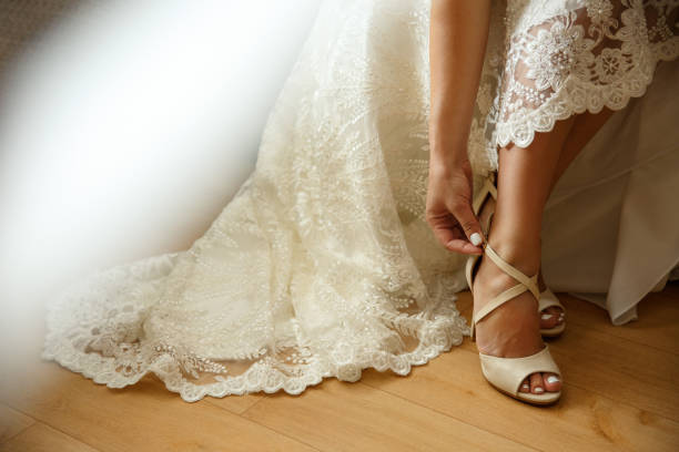 istock Bride puts on wedding shoes on high heels 1162297720
