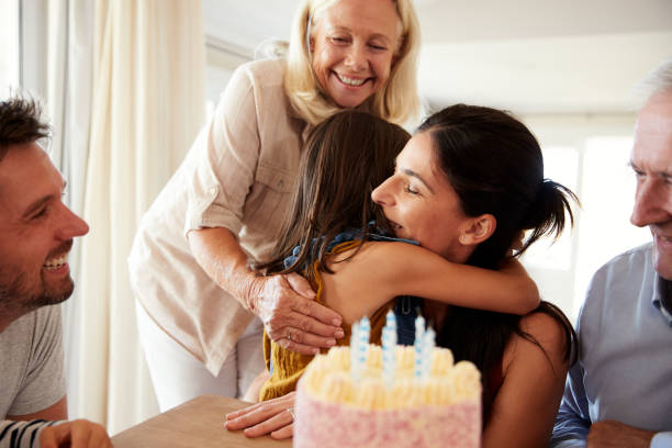 mujer adulta media abrazando a su hija después de soplar las velas en el pastel de cumpleaños, de cerca - birthday cake five people party fotografías e imágenes de stock