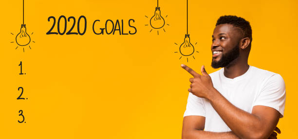 Cheerful black man pointing at checklist with 2020 goals