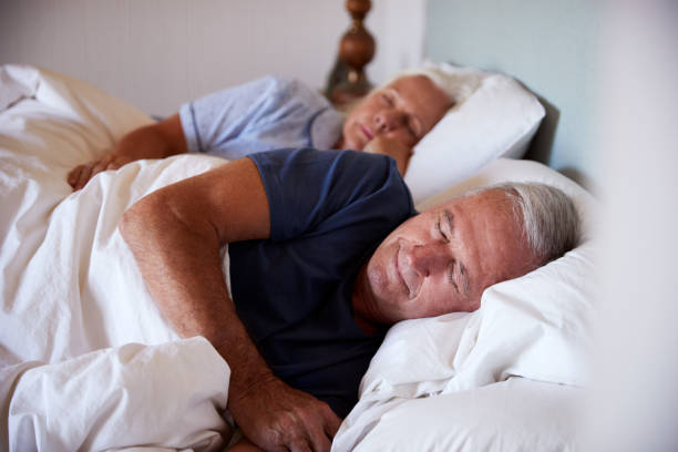 senior white couple asleep in their bed, waist up, close up - quilt 60s 70s activity imagens e fotografias de stock