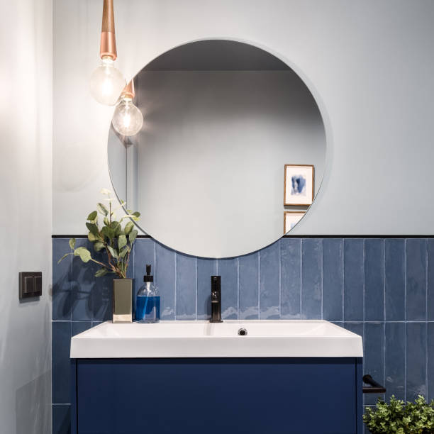 Bathroom with big round mirror Designed bathroom with stylish blue cabinet, blue wall tiles and big round mirror domestic bathroom stock pictures, royalty-free photos & images