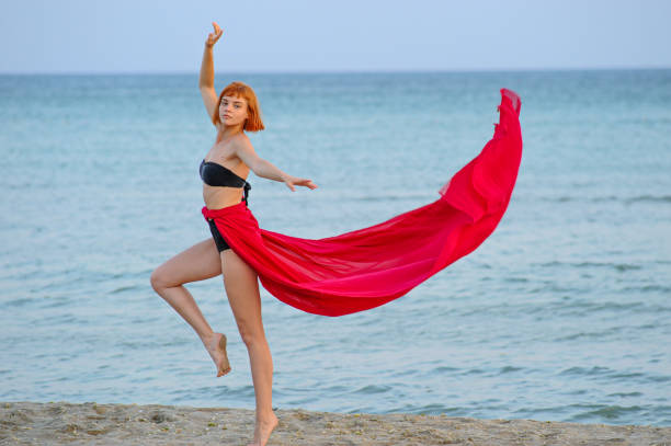 istock Woman in red dress run on beach 1162301408