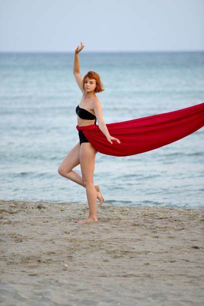istock Woman in red dress run on beach 1162301427