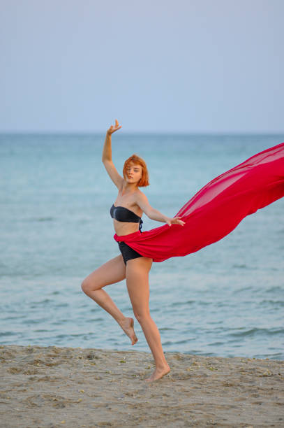 istock Woman in red dress run on beach 1162301433