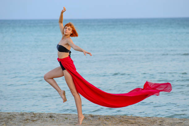istock Woman in red dress run on beach 1162301436