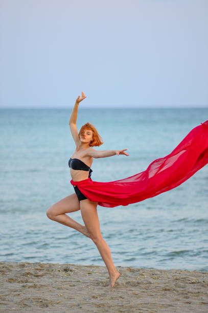istock Woman in red dress run on beach 1162301496