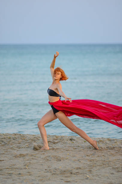 istock Woman in red dress run on beach 1162302020