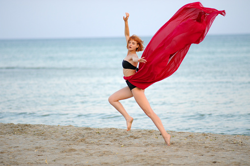 Woman in red dress run on beach
