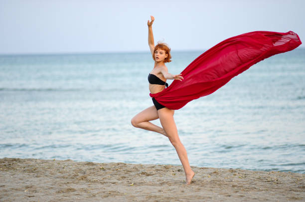 istock Woman in red dress run on beach 1162302026