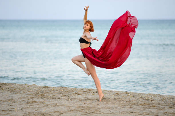 istock Woman in red dress run on beach 1162302041
