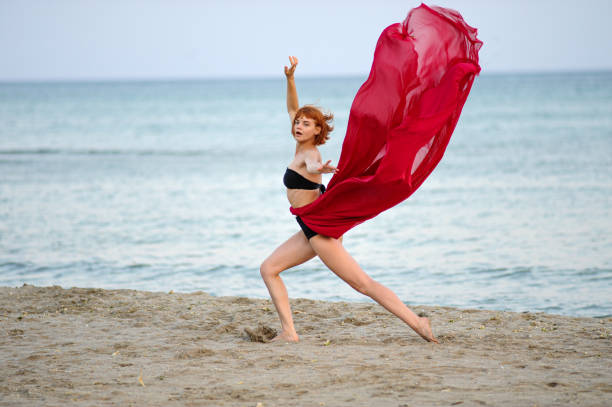 istock Woman in red dress run on beach 1162302068