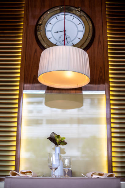 istock A nautical wall clock and an overhanging lamp above two table seats in a yachting style restaurant 1162302474