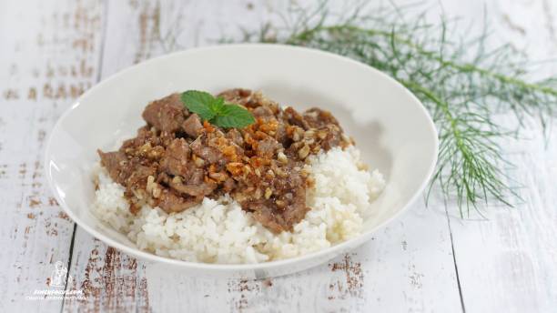 istock Stirred and fried pork with garlic and pepper served on steamed rice. Shooting in studio on backdrop for advertising. Thai and Asian food concept. 1162303328