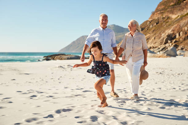 starsza biała para i ich wnuczka spacerująca po słonecznej plaży, z bliska - sunny cheerful close up outdoors zdjęcia i obrazy z banku zdjęć