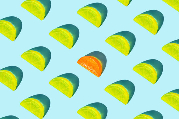istock Creative pattern of yellow citrus lemon slices and orange as ice for cocktail on blue background. 1162309543