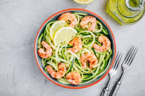 Spiralized zucchini noodles pasta with shrimps. Top view Spiralized zucchini noodles pasta with shrimps on gray stone background, top view courgette stock pictures, royalty-free photos & images