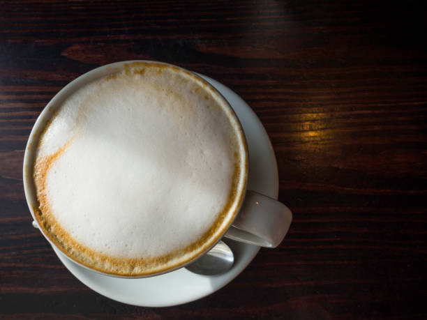 istock Cup of coffee with foam on wooden table, top view 1162319556