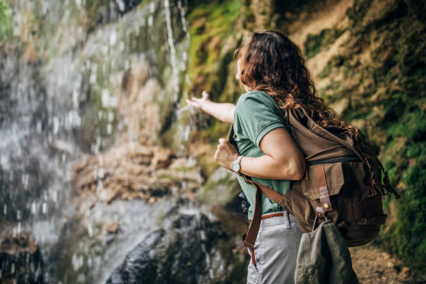 istock Woman standing by the waterfall 1162323196