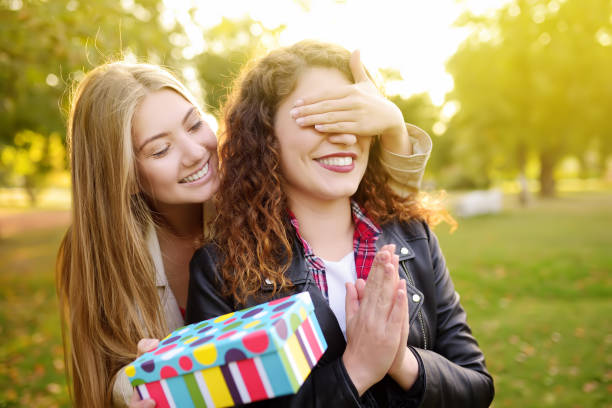 Beautiful young women gives a birthday gift to her friend Beautiful young women gives a birthday gift to her friend. Friendship. gift for girlfriend stock pictures, royalty-free photos & images