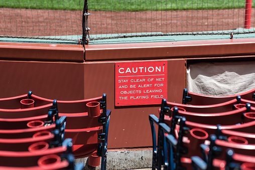 Field level section seating for the baseball fans to watch the game in the stadium has warning sign.