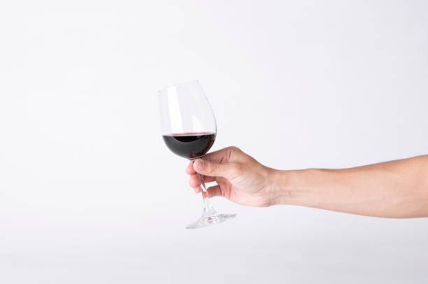 istock Man hand holding a wine glass on a gray background. 1162323617