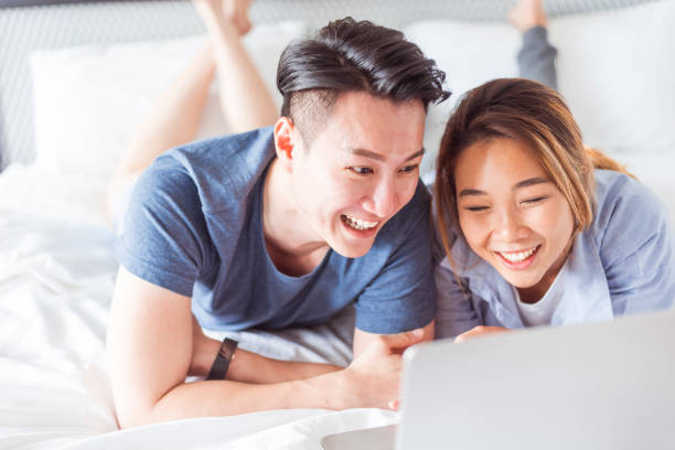 istock Happy Asian couple lying on the bed and using laptop 1162324306