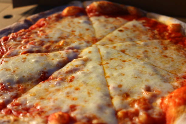 Image of sliced takeaway pizza in cardboard box from Italian restaurant pizzeria, eating slices of Neapolitan margherita pizza recipe margarita with melted mozzarella cheese, ragu tomato sauce and basil herbs, al fresco dining outdoors at night in garden