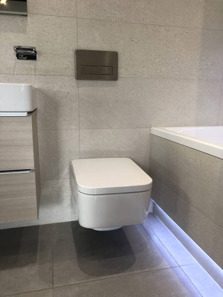 immagine della moderna suite da bagno di lusso bianca con moderna teglia da toilette appesa a parete quadrata appesa alla parete del bagno, grandi piastrelle di granito in pietra beige e pavimenti piastrellati, bagno con illuminazione a led impermeabile so - sink bathroom pedestal tile foto e immagini stock