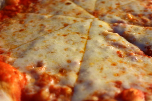 Image of sliced takeaway pizza in cardboard box from Italian restaurant pizzeria, eating slices of Neapolitan margherita pizza recipe margarita with melted mozzarella cheese, ragu tomato sauce and basil herbs, al fresco dining outdoors at night in garden