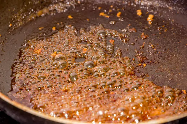 sugar caramelizing in a frying pan at the gas stove in the kitchen. Close up