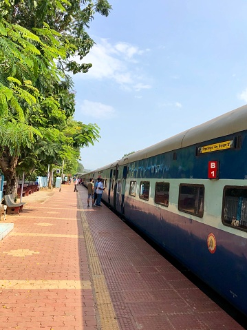 Karwar Railway Station, Uttara Kannada, Karnataka, India - April 2, 2019: Stock photo of train pulled into Karwar Railway Station platform with passengers waiting to get aboard.