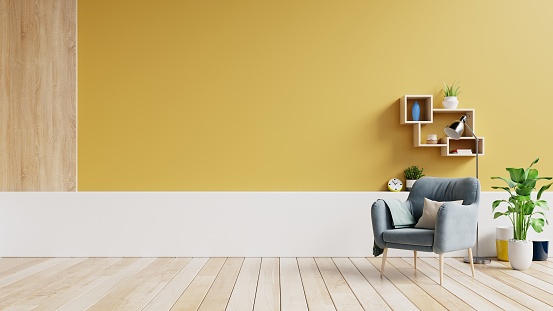 Living room interior with fabric armchair ,lamp,book and plants on empty yellow wall background.3d rendering