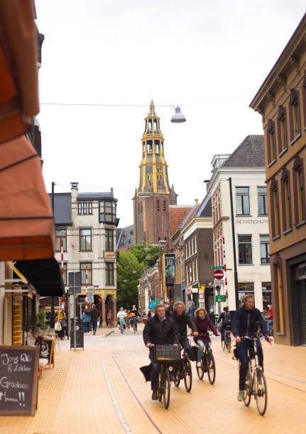 Groningen, Netherlands: Cyclists rIde down a street in downtown Groningen, with the steeple of the 15th-century Aa Church (Der Aa-Kerk) in the background.