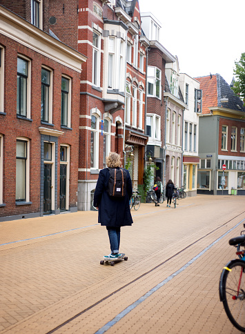 Groningen, Netherlands: A skateboarder with a backpack rides down the center of a main shopping (bricked) street in Groningen.
