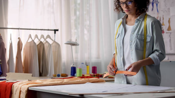 istock Professional seamstress marking patterns, considering dimensions of customer 1162337265