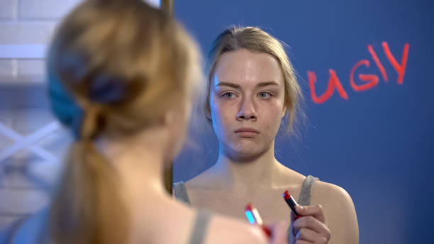 Depressed girl looking in mirror, word ugly written by lipstick, insecurities Depressed girl looking in mirror, word ugly written by lipstick, insecurities ugly people crying stock pictures, royalty-free photos & images