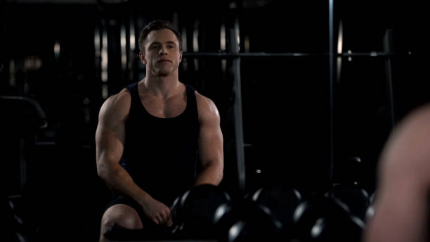 istock Bodybuilder looking at himself in mirror after workout, satisfied with results 1162337502