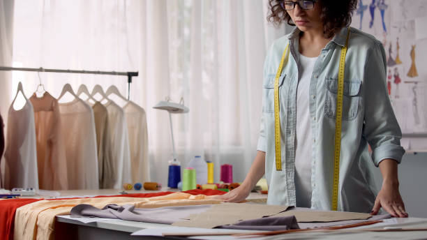 istock Concentrated on her work designer unfolding fabric on desk, personal atelier 1162337584