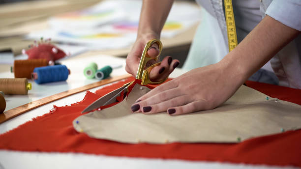 istock Student clumsily treating with scissors and cloth trying to cut out pattern 1162338285
