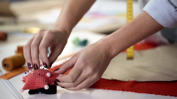 istock Girl taking pins from needles pad and fixing template on fabric before cutting 1162338290