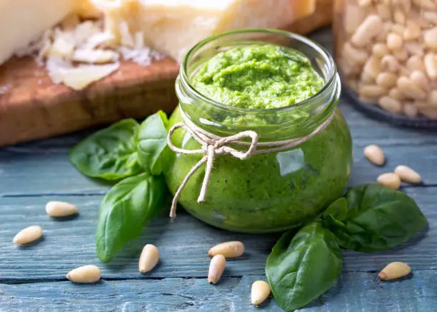 Homemade pesto with pine nuts on a blue wooden background