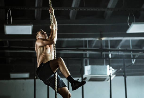 istock Young athletic man exercising strength on a rope in a gym. 1162339830