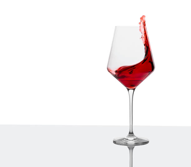 Glass of red wine with splashes on white table. Vertical orientation