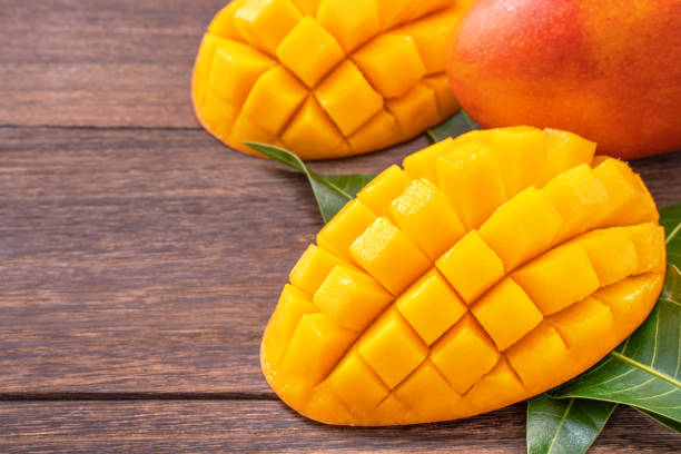 istock Fresh mango - beautiful chopped fruit with green leaves on dark wood background. Tropical fruit design concept. Flat lay. Top view. Copy space. 1162345152