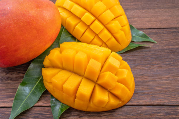 istock Fresh mango - beautiful chopped fruit with green leaves on dark wood background. Tropical fruit design concept. Flat lay. Top view. Copy space. 1162345202