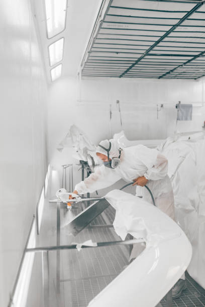 istock Worker spraying car parts with white paint. 1162346338