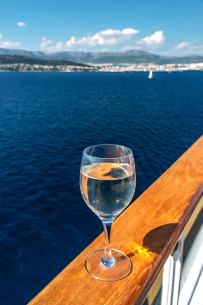 A glass of white wine on the rail of a cruise ship.